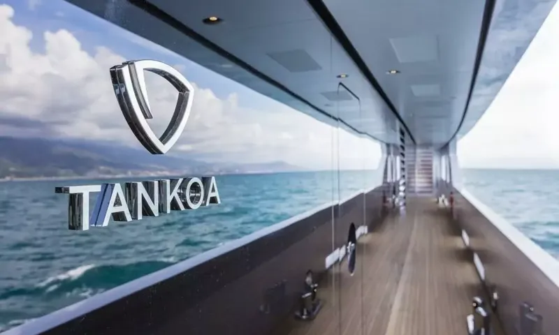 Suerte: Metal builder logo on glass beside a teak side deck with sea view