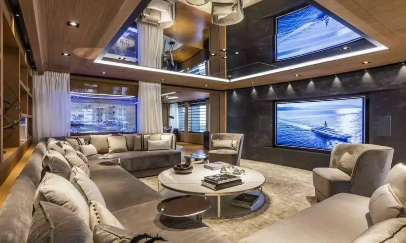 Suerte: Lounge with grey sofas, round coffee table, large wall screen and a lit aquarium
