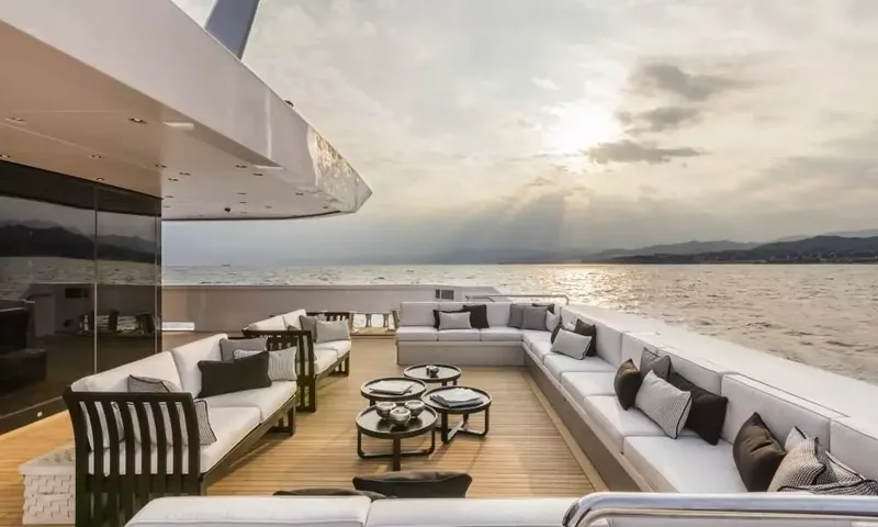 Suerte: Teak deck with wraparound white sofas and small round tables overlooking the sea at sunset