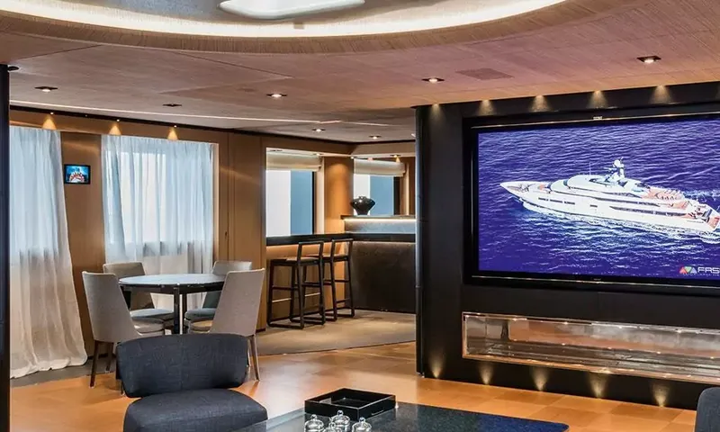 Suerte: Lounge with large wall screen, round game table, chairs and a small bar