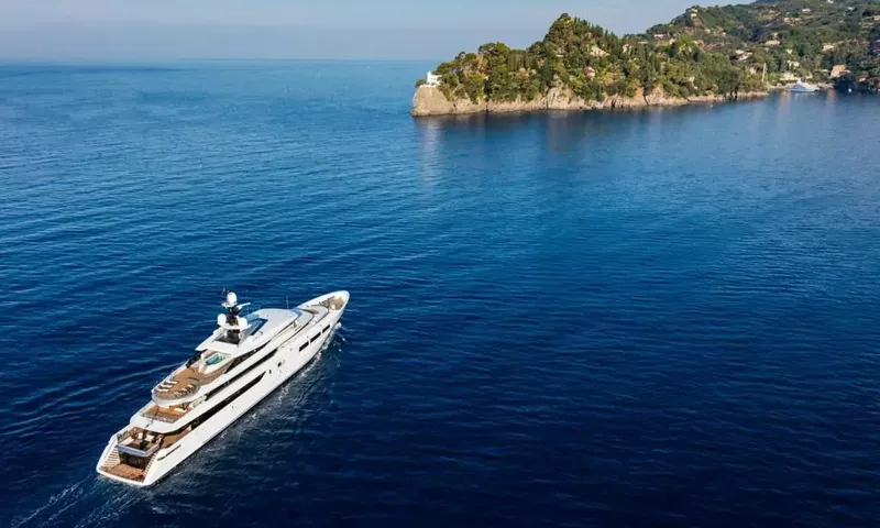 Suerte: Yacht on deep blue water heading toward a wooded headland