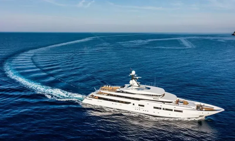Suerte: White superyacht cruising on deep blue sea leaving a long curved wake