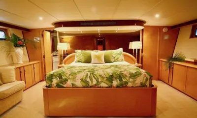 Suite Life: Cabine ampla com cama de casal central com roupa de cama estampada de folhas e armários de madeira