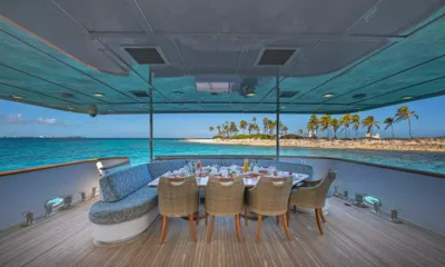 Sweet Escape: Covered outdoor dining table with wicker chairs facing turquoise sea and palm island