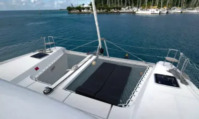 Grande Croisiere: Redes de trampolim no convés de proa com almofadas de sol pretas com vista para uma marina