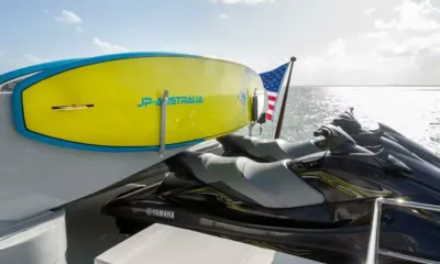 Temptation: Yellow paddleboard mounted on the deck beside two stowed jet skis