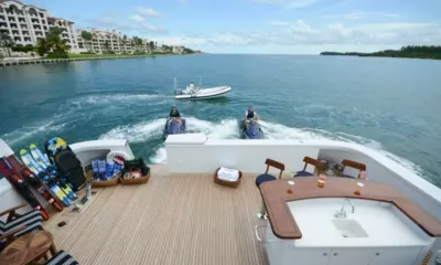 Themis: Esquis aquáticos e wakeboards em um convés de teca enquanto dois jet skis e um bote auxiliar navegam atrás