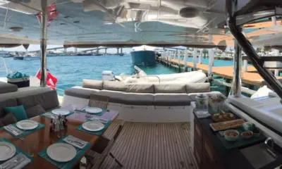 Tiger Lily: Shaded aft deck with set dining table, cushioned seating and tender behind, overlooking a marina