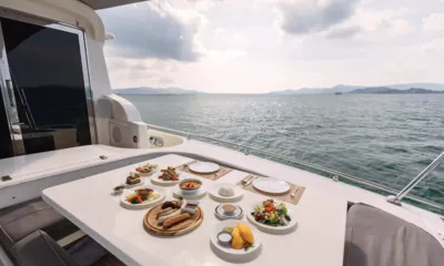 Moon Glider: Aft deck table set with a meal facing open sea and distant hills