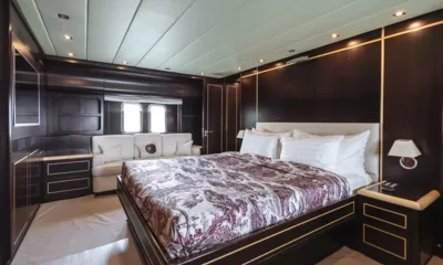 Moon Glider: Double cabin with patterned bedspread, dark wood panelling, white sofa and two portholes