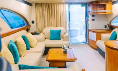 Monica: Salone con divani crema, cuscini verde acqua e gialli, tavolino in legno e porta in vetro verso il ponte
