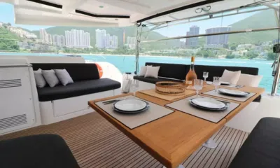 Mando: Outdoor teak dining table set with plates, glasses and a bottle of wine in the cockpit