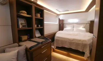 Mando: Cabin with double bed, wooden shelves holding a hat and books, and folded towels