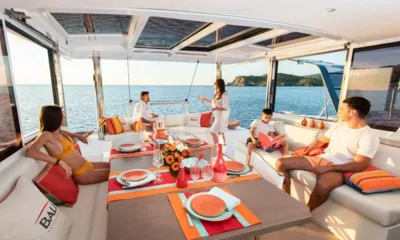Happy Fifty: Famiglia riunita attorno a un tavolo apparecchiato in un salone aperto rivolto al mare