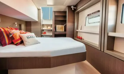 Happy Fifty: Cabina con letto matrimoniale, cuscini a righe, mensole e una finestra nello scafo