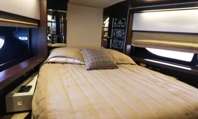 Utopia: Cabina con letto matrimoniale in lino beige, cuscino decorato e finestre sullo scafo