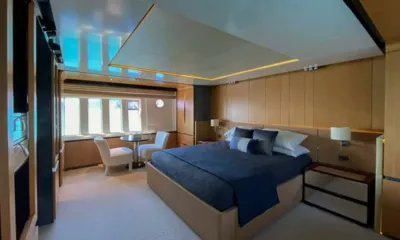 Amazing Grace: Cabine grande com cama de casal coberta em azul marinho, painéis de madeira e mesa pequena junto às janelas