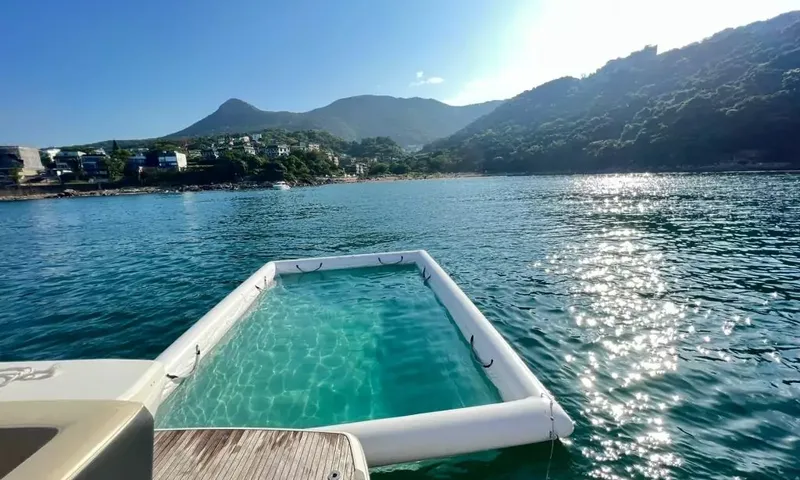Bavaria Fly: Inflatable sea pool floating behind the stern, with green hills and houses on the shore