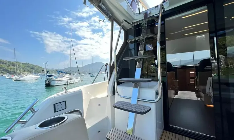 Bavaria Fly: Aft deck with steel steps up to the flybridge beside glass doors into the saloon