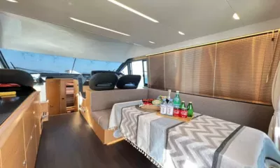 Bavaria Fly: Saloon with bench seating around a table set with drinks, helm seats forward