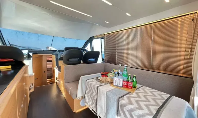 Bavaria Fly: Saloon with bench seating around a table set with drinks, helm seats forward