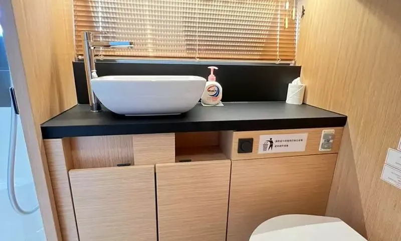 Bavaria Fly: Bathroom with a white vessel sink on a dark counter above wood cabinets