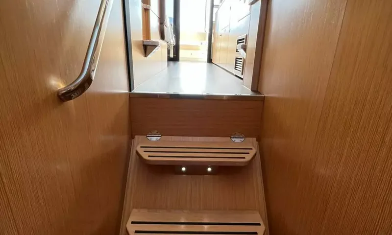 Bavaria Fly: Wooden companionway steps with handrail leading up to the saloon