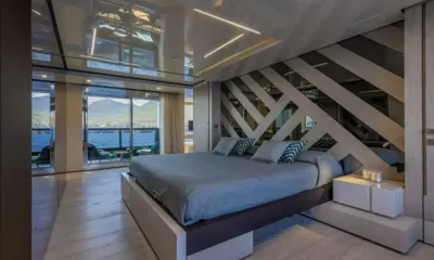 Emocean: Ampia cabina con letto grigio, testiera a pannelli diagonali e porte di vetro che danno su una terrazza privata