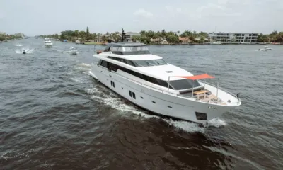 Fifty Shades: Iate a motor branco navegando por um canal ladeado de palmeiras e casas