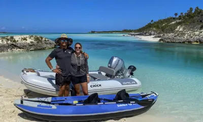 Kittiwake: Dois membros da tripulação em uma praia com um bote auxiliar inflável e um caiaque inflável azul