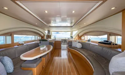 Legend & Soul: Saloon with grey leather sofas, oval table and wood floor leading to the galley and windows