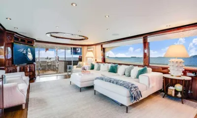 Namastay: Salão principal iluminado com sofá modular branco, televisão e grandes janelas com vista para o mar