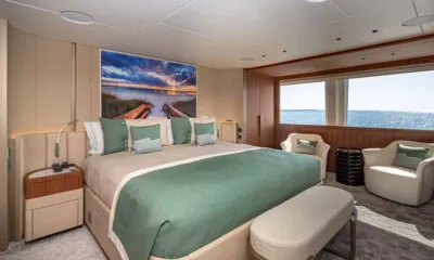 Rising Dawn: Cabine ampla com cama de detalhes verdes, poltronas e amplas janelas para o mar