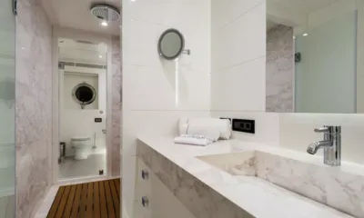 S7: Banheiro de mármore com pia, espelho, chuveiro de chuva e vaso sanitário separado