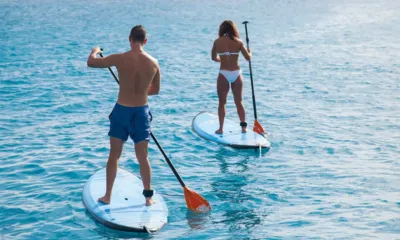 Cat & The Fiddle: Duas pessoas praticando stand up paddle em água turquesa cristalina