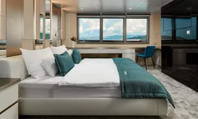 Ohana: Cabine com grande cama de casal, manta e almofadas verde azulado, escrivaninha e janelas para a costa