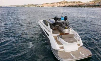 Fellow III: Vista rialzata della poppa dello yacht con salotto di poppa e piattaforma bagno in teak vicino a una città sulla collina