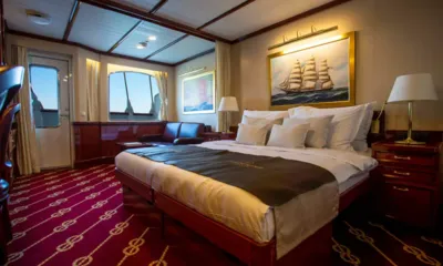 Golden Horizon: Cabine com cama de casal, sofá de couro, janelas grandes e quadro de um veleiro