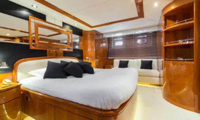 Accama Delta: Cabine dupla com cama branca, almofadas pretas, painéis de madeira, sofá e espelho