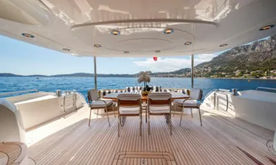 Lady Yousra: Mesa de jantar coberta no deck de popa com seis cadeiras e almofadas listradas voltada para o mar e as colinas