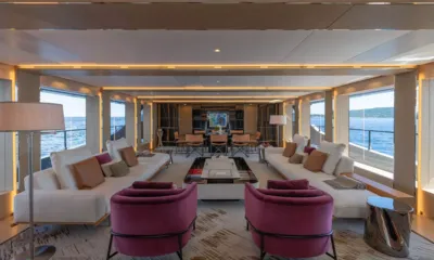 Lel: Salón largo con sofás blancos, sillones rosas y zona de comedor al fondo, grandes ventanales