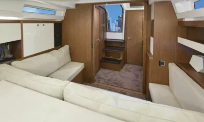 Love: Sala inferior com sofás creme e painéis de madeira, degraus que sobem por uma porta