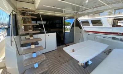 Male IV: Deck de popa de teca com mesa coberta, escadas para o deck superior e portas para o salão