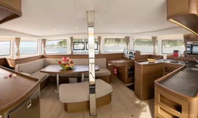 Lagoon 420: Salão com janelas panorâmicas, mesa de jantar com flores, assentos estofados e bancadas de cozinha em madeira