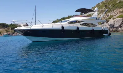 Chill Out II: Yacht a motore con scafo scuro all'ancora in acque blu limpide accanto a una costa rocciosa