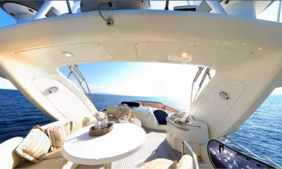 Chill Out II: Flybridge con tavolo rotondo, sedute imbottite e postazione di guida sotto un hardtop con vista sul mare
