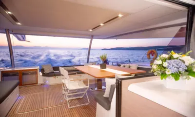 Dolly: Mesa de jantar no convés de popa coberto com flores e esteira ao pôr do sol