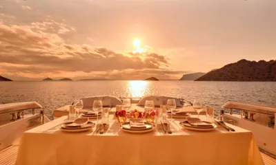 For Ever: 夕暮れの海を望む、皿とグラスと花が並ぶ屋外のテーブル