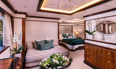 Idyllic: Cabine com cama de colcha azul-esverdeada, sofá, cômoda de madeira, espelho e orquídeas brancas