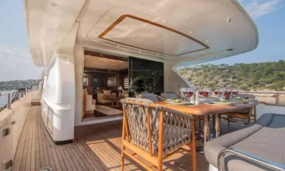 Salty: Table du pont arrière dressée pour un repas avec verres à vin, portes du salon ouvertes derrière
